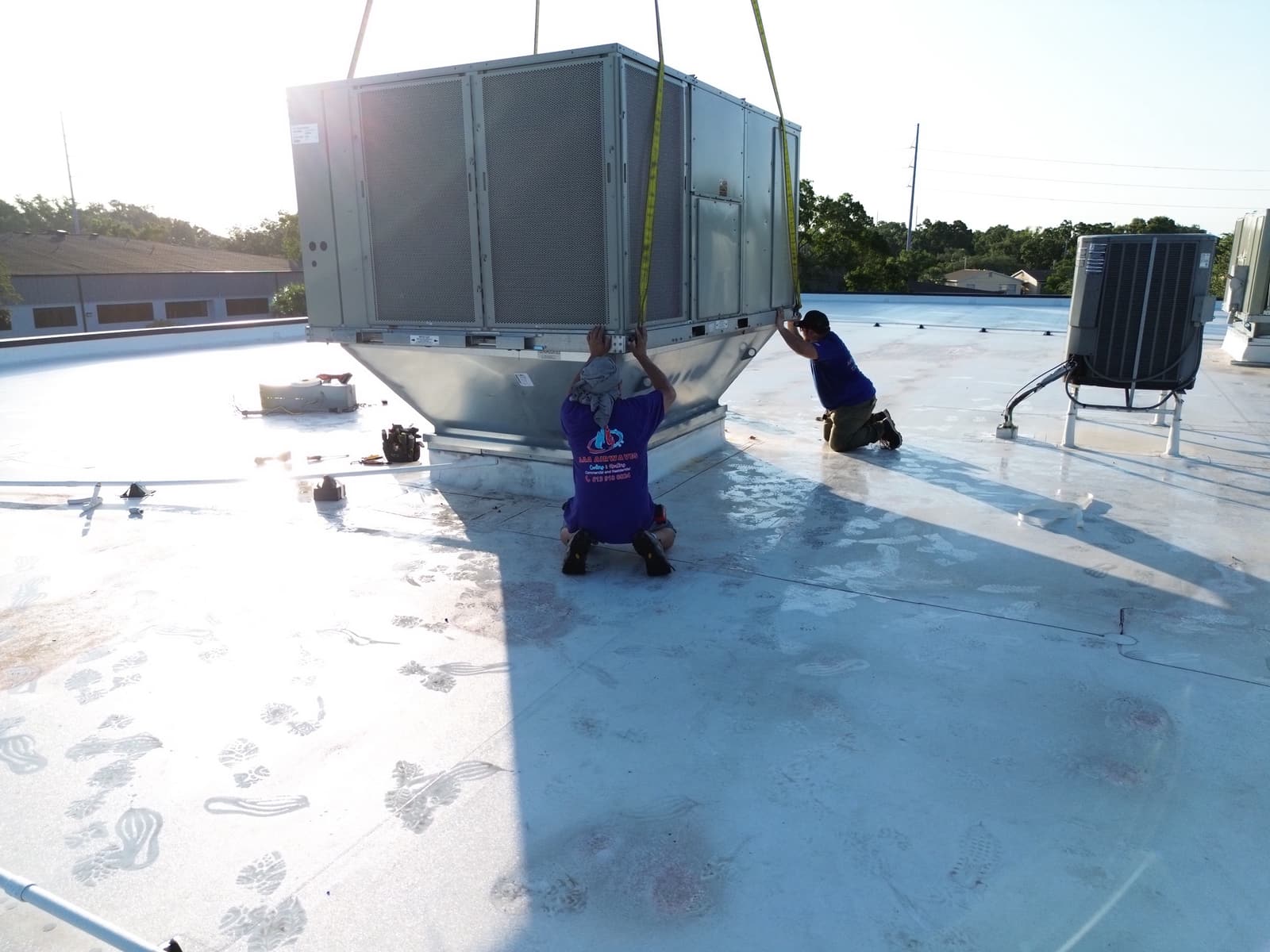 AAA Airwaves technicians guiding a rooftop HVAC unit during installation